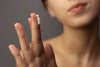 Close-up of a woman applying retinol to her fingertip, demonstrating proper retinoid usage in a skincare routine for sensitive or acne-prone skin.